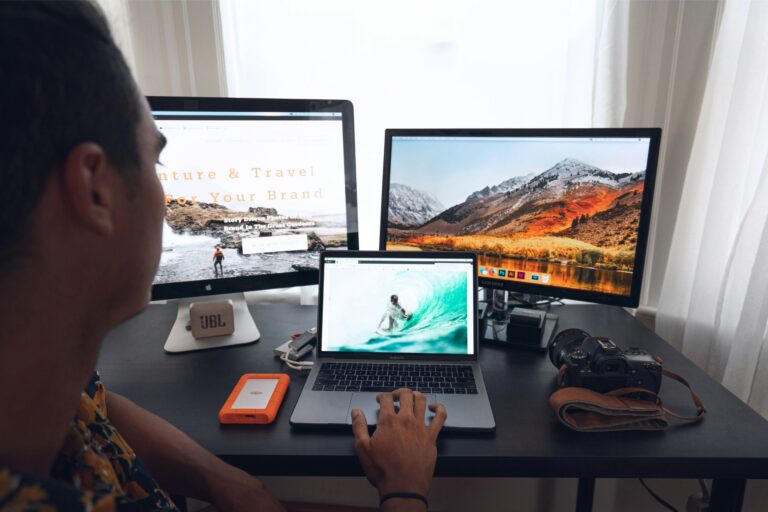 A person sitting at a desk looking at several computer screens at one time.