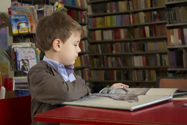 A young child reading a book at a table.